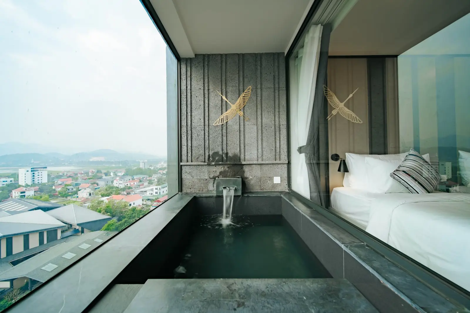 Bồn onsen đá riêng cạnh giường, cửa kính nhìn ra thị trấn – phòng Deluxe Lynntimes Thanh Thủy