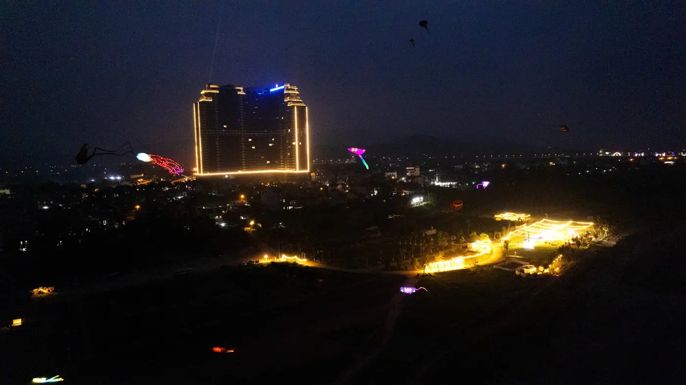Tòa khách sạn 32 tầng Lynntimes Thanh Thủy (Wyndham Thanh Thủy cũ) sáng đèn về đêm nhìn từ bãi cỏ ven sông Đà