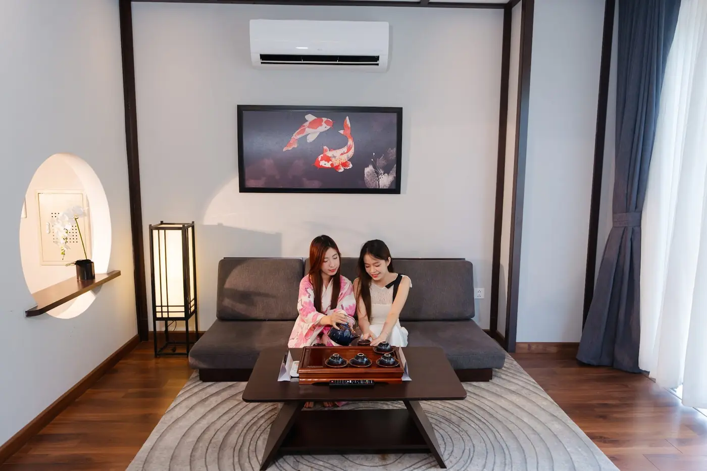 Hai cô gái thưởng trà ở phòng khách Shoptel với tranh cá Koi – Lynntimes Thanh Thủy